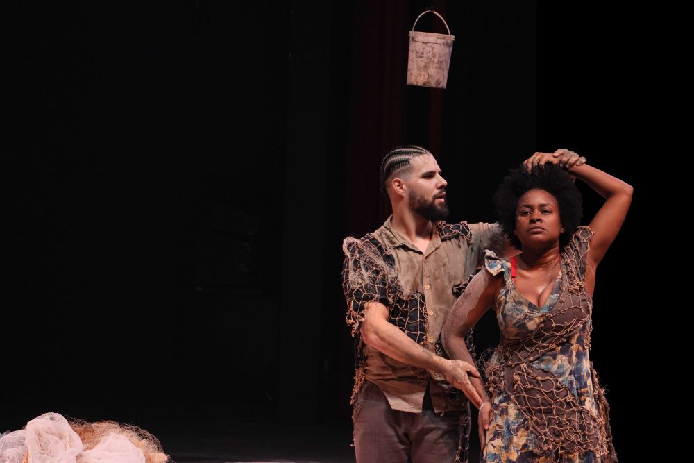 Inédito em Curitiba, releitura da obra de Chico Buarque e Paulo Pontes, “Gota d’Água”, chega à CAIXA Cultural Curitiba Montagem da Cia Baiana de Teatro Brasileiro tem apresentações de 29 de outubro a 8 de novembro  Augusto Nascimento e Evana Jeyssan em cena (Foto: Victor Blvk) De 29 de outubro a 8 de novembro, a CAIXA Cultural Curitiba recebe a adaptação da obra de Chico Buarque e Paulo Pontes, “Gota d’Água”, da Cia Baiana de Teatro Brasileiro. Inédito na capital paranaense, a montagem tem direção artística de Vinícius Lírio, concepção e codireção de Augusto Nascimento e produção da Capricórnio Produções.  O espetáculo, cuja narrativa original é ambientada em um conjunto habitacional, transfere a narrativa para o Porto das Sardinhas, em Plataforma, no subúrbio ferroviário de Salvador e inserindo referências culturais e sociais, incorporando a pesca artesanal, as relações comunitárias e o cotidiano da região.
